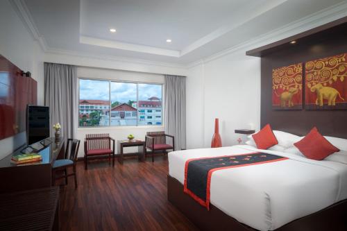 ein Hotelzimmer mit großem Bett und Schreibtisch in der Unterkunft Memoire d' Angkor Boutique Hotel in Siem Reap