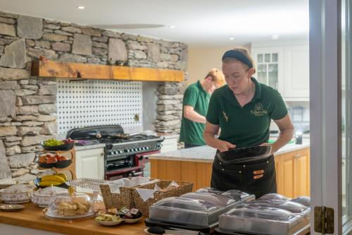 a woman standing in a kitchen preparing food at Tobervilla Guest House in Caherdaniel