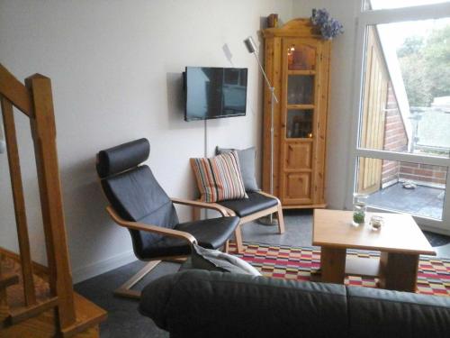a living room with a couch and a chair and a tv at Ferienwohnung Deichblick in Schillig