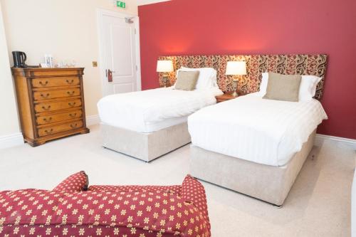 two beds in a room with a red wall at Tobervilla Guest House in Caherdaniel