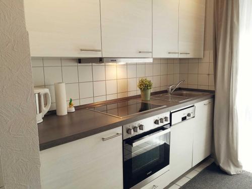 a kitchen with white cabinets and a sink and a stove at Ferienwohnung Boje 7 in Schillig