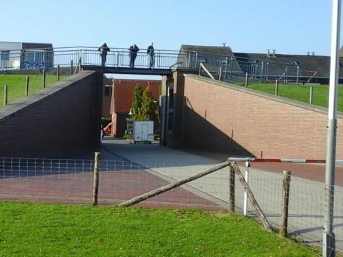 two people walking on a bridge over a building at Ferienwohnung Deichblick in Schillig