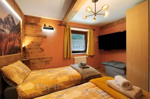 a bedroom with two beds and a television in it at Le rêve d'Emilie - Family house in Valtournenche