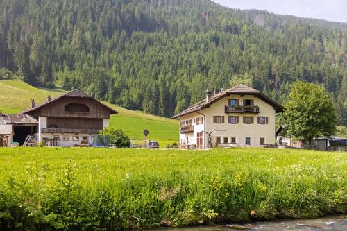 a large house in a field next to a mountain at Untersinnerhof Gsies in Valle Di Casies