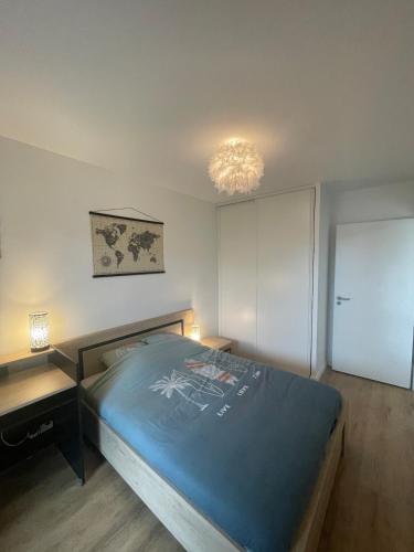 une chambre avec un lit et un lustre dans l'établissement Appartement en rez-de-jardin, à Lacanau