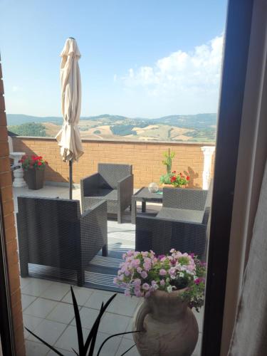 a balcony with a table and an umbrella and flowers at Bella Todi Apartment in Todi