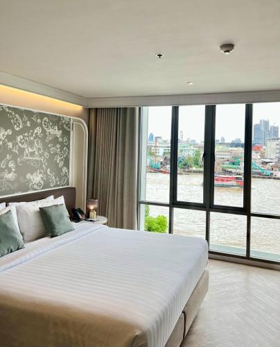 a bedroom with a large bed with a large window at The Quarter Chaophraya by UHG in Bangkok
