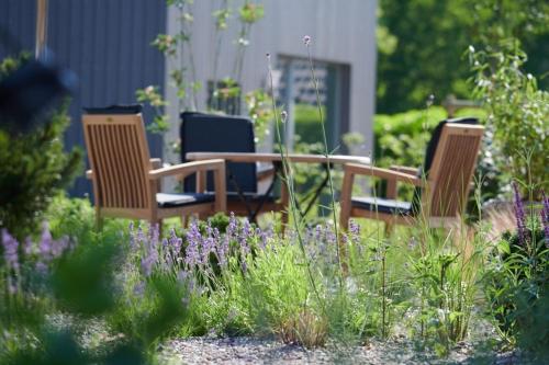 three chairs and a table in a garden with purple flowers at Elsas Enkel - Ferienwohnung Lotte in Waabs