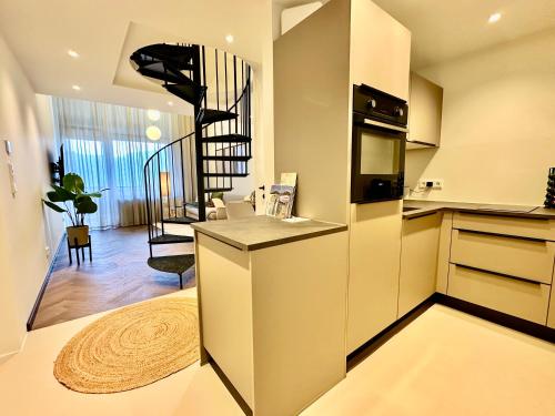 a kitchen with a staircase and a living room at Das Alpenzeit Loft mit Balkon und Grimmingblick in Bad Mitterndorf