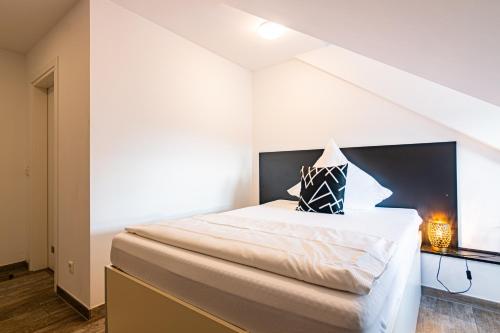 a bedroom with a large white bed with a black headboard at Nine Rooms - Serviced Rooms in Karlsruhe
