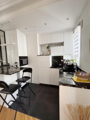 une cuisine avec des armoires blanches et un comptoir noir dans l'établissement Casama, à Paris