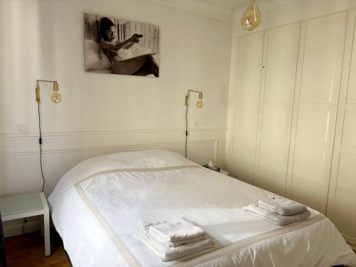 - un lit blanc dans une chambre avec une photo sur le mur dans l'établissement Casama, à Paris