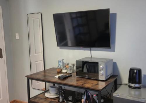Un microondas sobre una mesa con un televisor en la pared. en Amper Daar, en Beaufort West