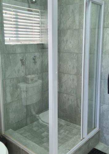 a bathroom with a shower with a glass door at Amper Daar in Beaufort West