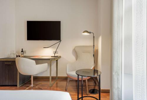 a living room with a desk and two chairs and a table at NH Collection Salamanca Palacio de Castellanos in Salamanca
