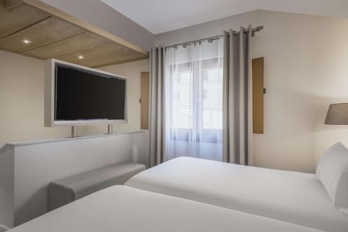 a bedroom with two beds and a flat screen tv at NH Collection Salamanca Palacio de Castellanos in Salamanca