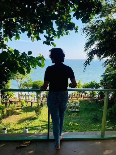 a woman walking on a porch looking out at the ocean at Asteya in Varkala