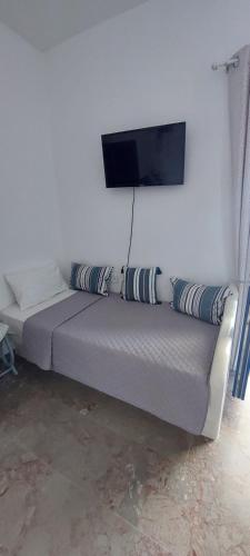 a bed in a room with a tv on the wall at Kalliopis Rooms in Katapola