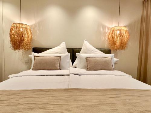 a bedroom with two beds with white pillows and two lights at Das Alpenzeit Loft mit Balkon und Grimmingblick in Bad Mitterndorf
