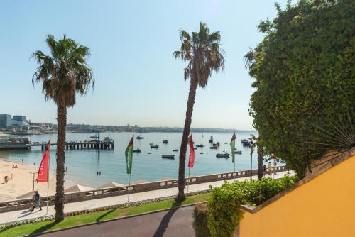 a beach with palm trees and boats in the water at Cascais Bay in Cascais