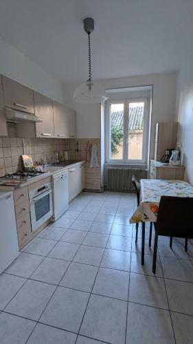 - une cuisine avec des appareils électroménagers blancs et une table dans l'établissement 75m2 - 2min centre piéton & 10 min de la gare, à Mulhouse