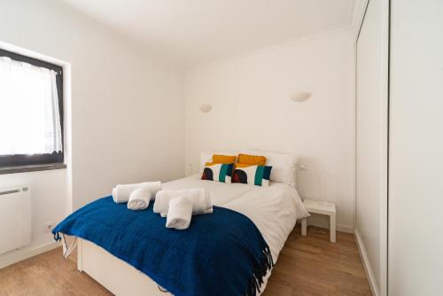 a white bedroom with a large bed with blue blanket at Cascais Bay in Cascais