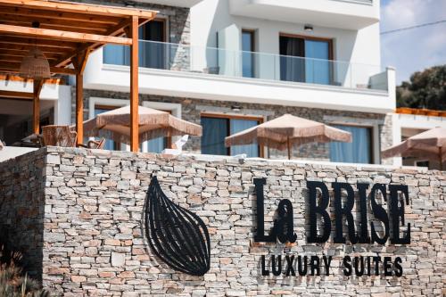 a sign on a wall with umbrellas in front of a building at La Brise Luxury Suites in Néa Péramos
