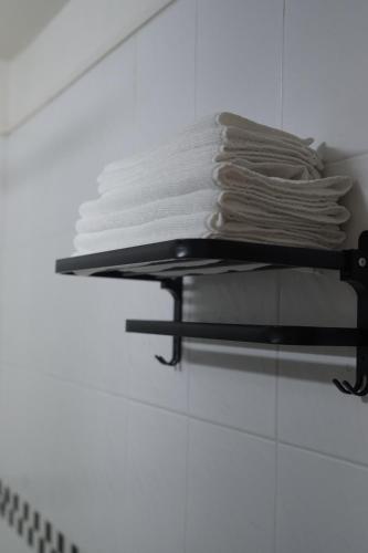 a stack of white towels on a shelf in a bathroom at CHACHA Stay 초코 Hongdae Apartment 1min to station 弘大 ホンデ in Seoul