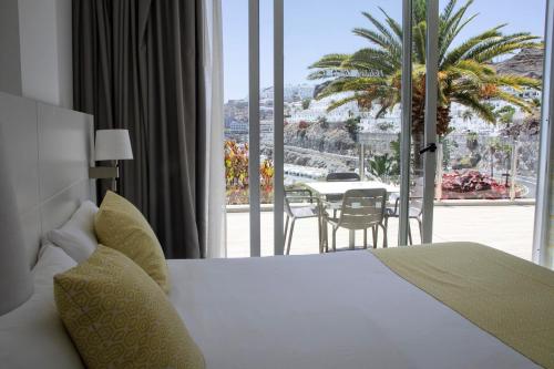 a bedroom with a bed and a balcony with a table at Holiday Club Puerto Calma in Puerto Rico de Gran Canaria