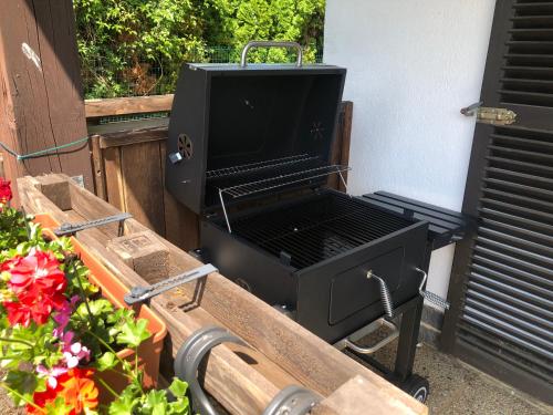 a black barbecue grill sitting next to some flowers at La Chouette du Freyr 3 chambres in Dinant