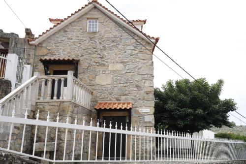 uma antiga casa de pedra com uma cerca branca em Stone House em Salzedas