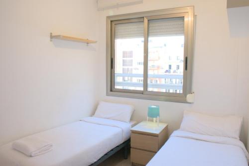 two beds in a room with a window at SWEET BCN Plaza Universidad in Barcelona