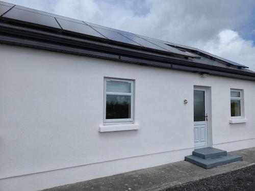 a white house with a solar roof at Teachín an tSrutháin in Galway