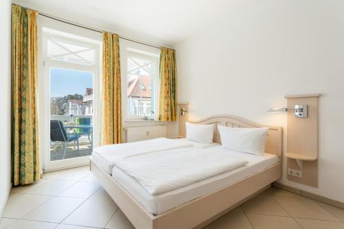 a bedroom with a bed and a large window at Haus Strandburg - hinter Düne und Meer in Binz