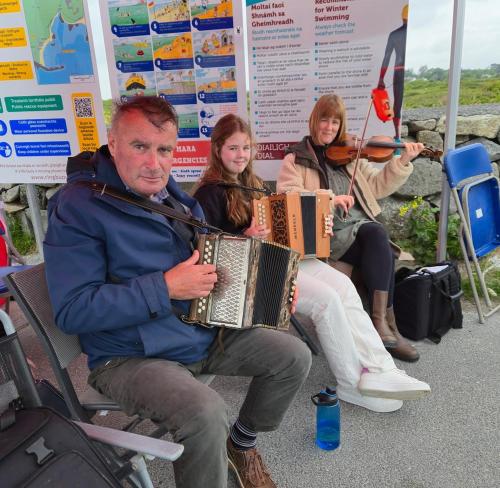 a group of people sitting on a bench with music at Teachín an tSrutháin in Galway