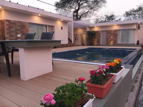 a house with a swimming pool and some flowers at Tattvam Farm Stayz & Swimming Pool in Kālka