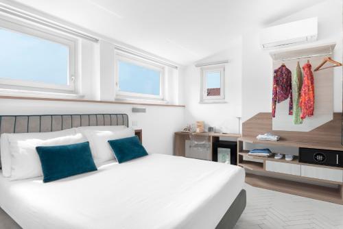 a white bedroom with a large white bed with blue pillows at Palazzo Tasso in Sorrento