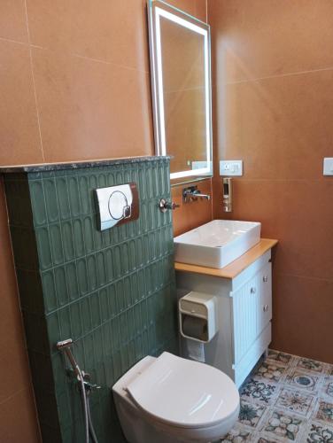 a bathroom with a toilet and a sink and a mirror at Tattvam Farm Stayz & Swimming Pool in Kālka