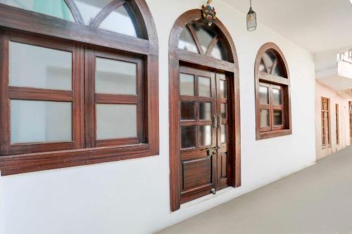 a pair of wooden doors on a white wall at Hotel O Khajuraho Central in Khajurāho