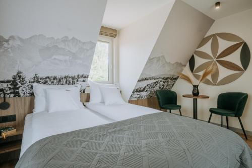 a bedroom with a large bed and two green chairs at Willa Bachledzki Wierch 12 in Zakopane