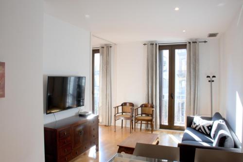 a living room with a couch and a tv at SWEET BCN Rambla 48 in Barcelona