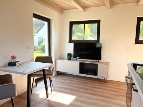 a living room with a flat screen tv and a table at Ferienwohnung Laran - direkt am Bodden in Ralswiek in Ralswiek