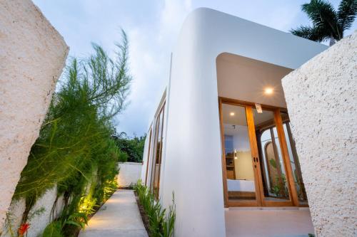 a white house with glass doors and plants at Asri Village Two in Uluwatu