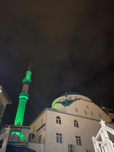 a mosque with a green light in front of a building at Zin D Home Otel Cekmeköy in Istanbul
