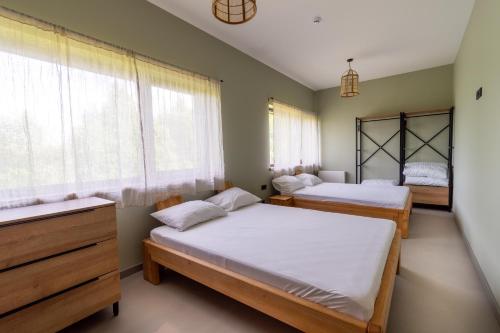 two beds in a room with two windows at Viešbutis - restoranas SAKAI in Gribžiniai