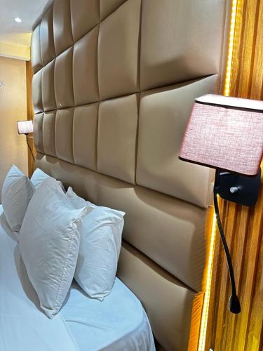 a bedroom with a bed with a padded headboard and a lamp at Golden Tulip Hotel Port Harcourt -GTPH in Port Harcourt