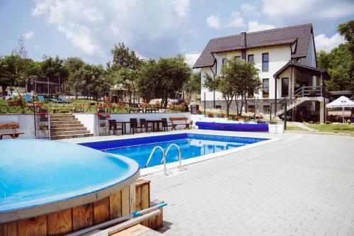 a swimming pool with a hot tub next to a house at Pensiunea Casa Dacilor in Podeni