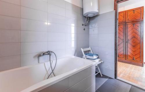 a white bathroom with a tub and a glass door at Villa Leggiero in Fažana