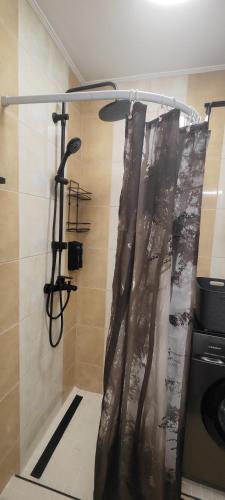 a shower with a shower curtain in a bathroom at Студио Sand, к-с Нестинарка in Tsarevo