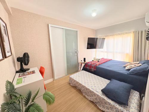 a bedroom with a blue bed and a television at Apê Refúgio Urbano in Brasilia